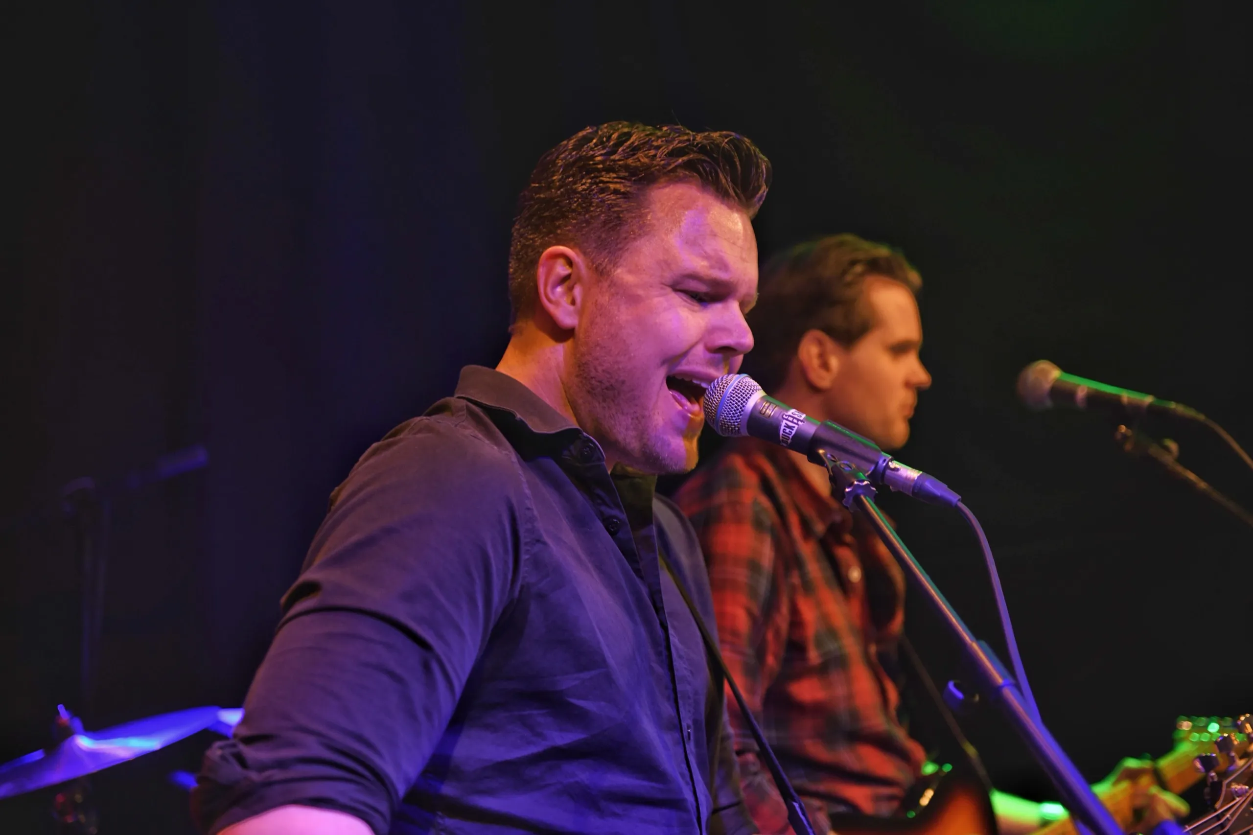 Zanger vol in de microfoon tijdens een clubshow