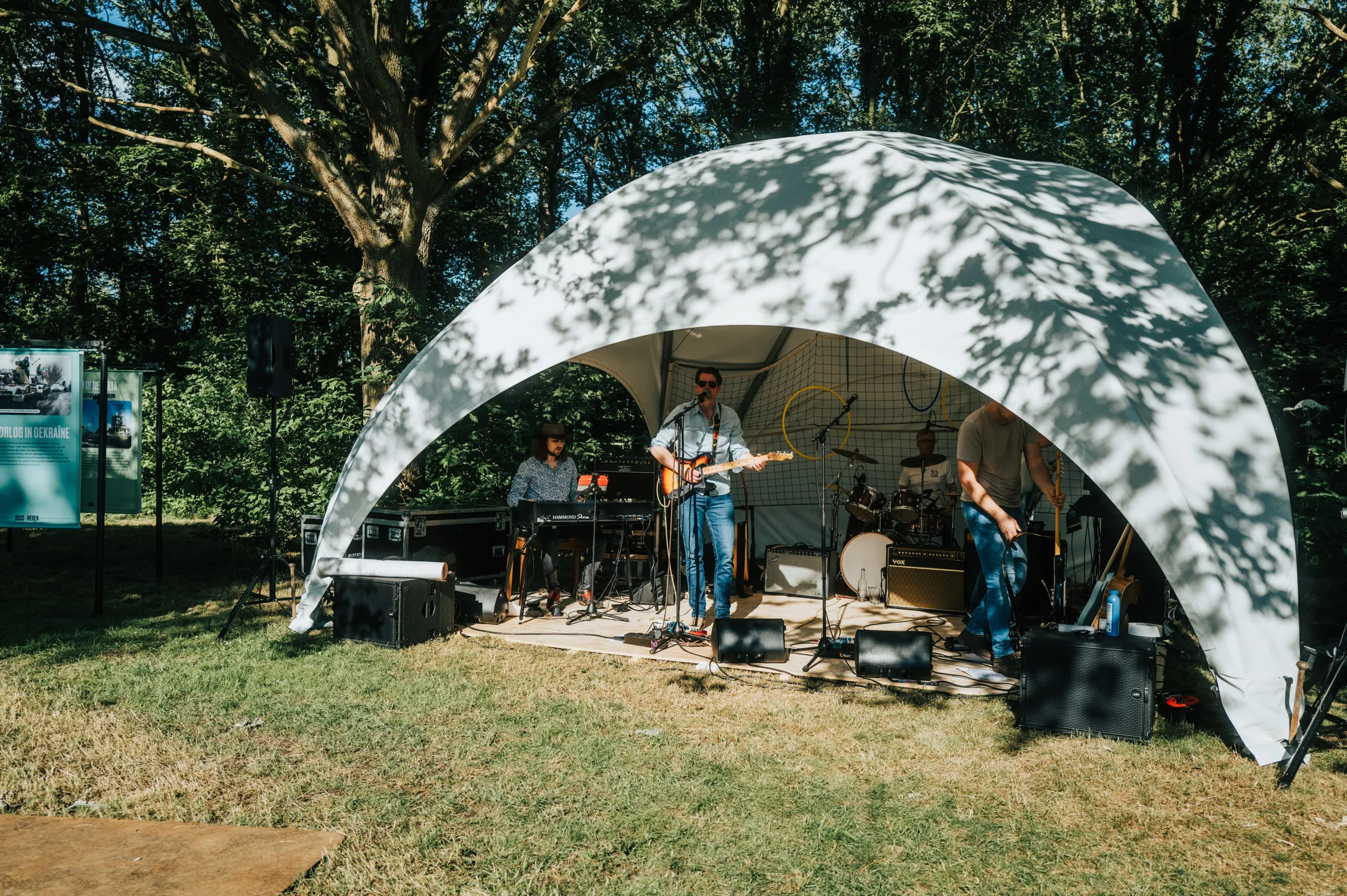 Het festivalterrein met tent en bomen tijdens het optreden